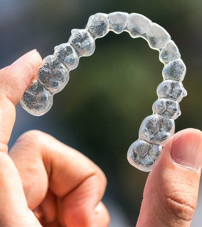 Hand holding an Invisalign clear braces treatment