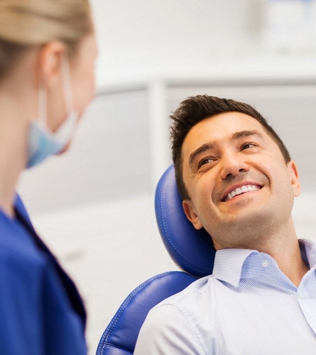 Man in dental chair smiling at dentist