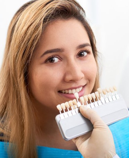 cosmetic dentist in Tyler holding a row of veneers up to a patient’s smile